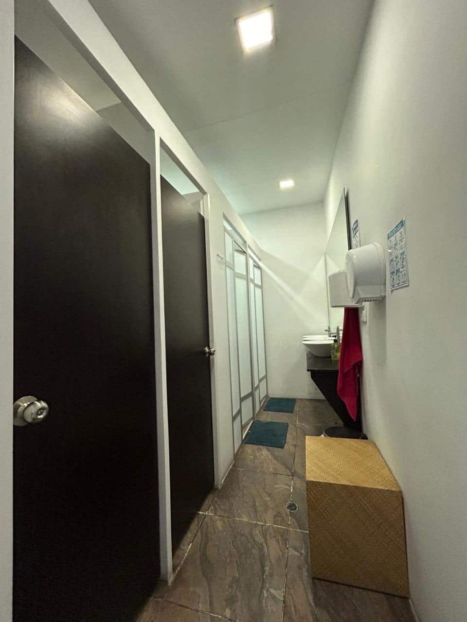 Pasillo de los baños compartidos con puertas negras y lavamanos