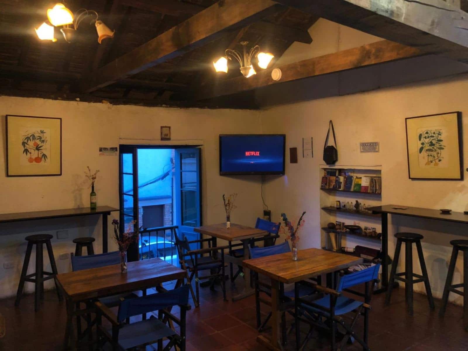 Café con mesas de madera, sillas azules y techo de vigas