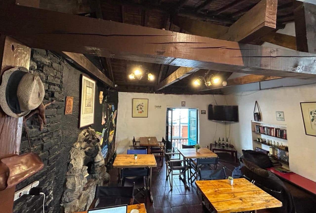 Café con pared de piedra, vigas de madera y biblioteca