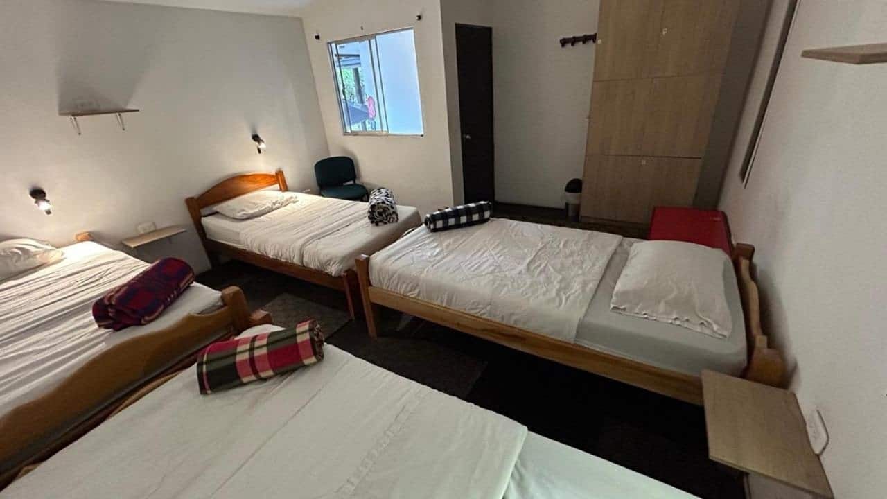 Dormitorio con cuatro camas sencillas y cobijas