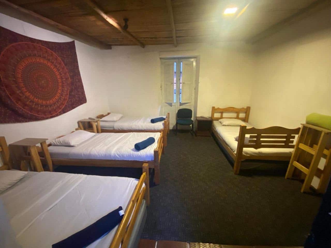 Dormitorio con cuatro camas sencillas de madera, sin camarotes