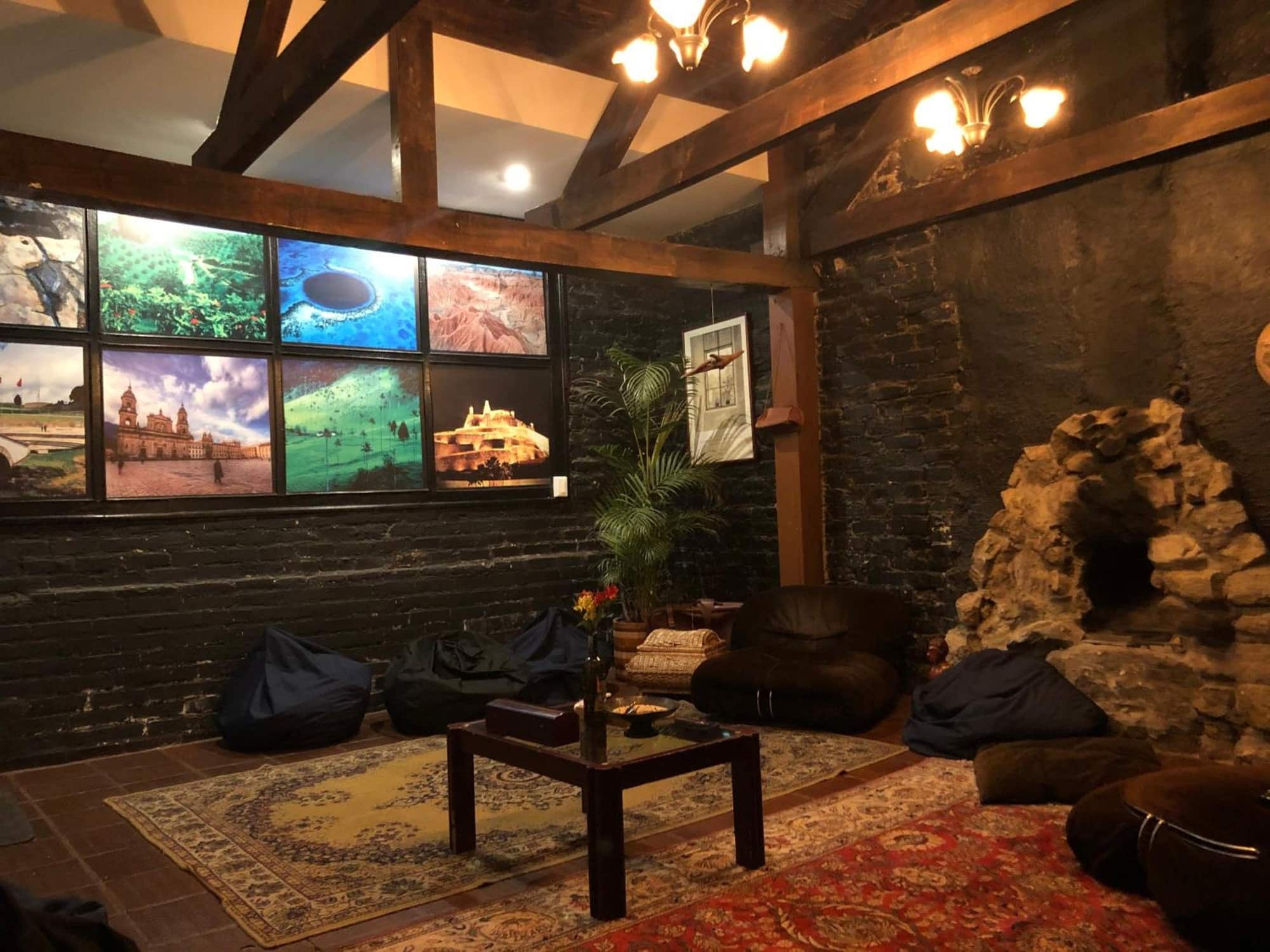Sala con puffs, mesa baja, chimenea de piedra y vigas