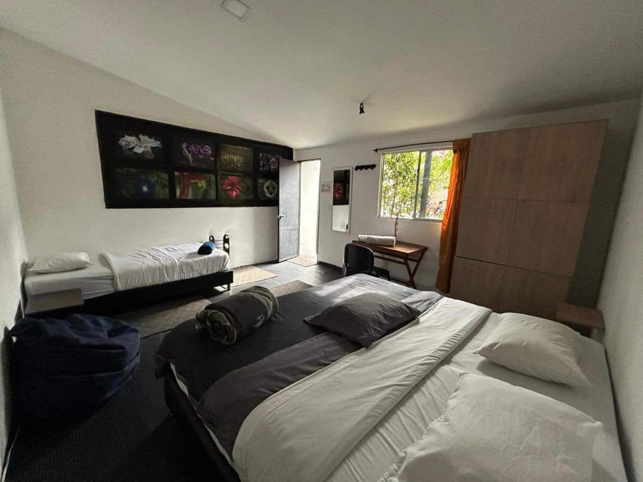 Habitación con cama king y una cama sencilla, cuadros de flores