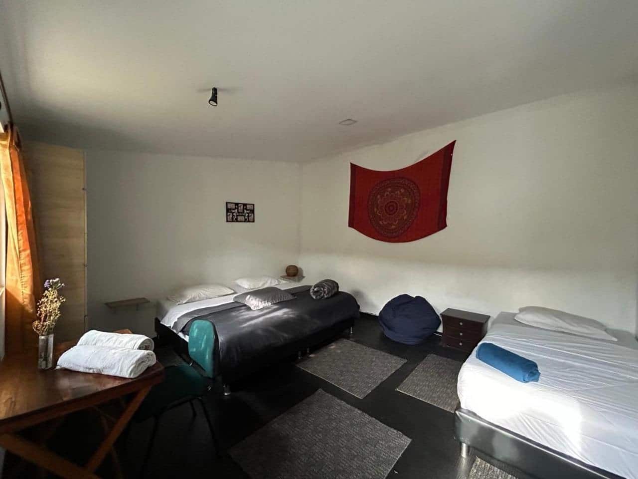 Habitación con dos camas, tapiz rojo y escritorio
