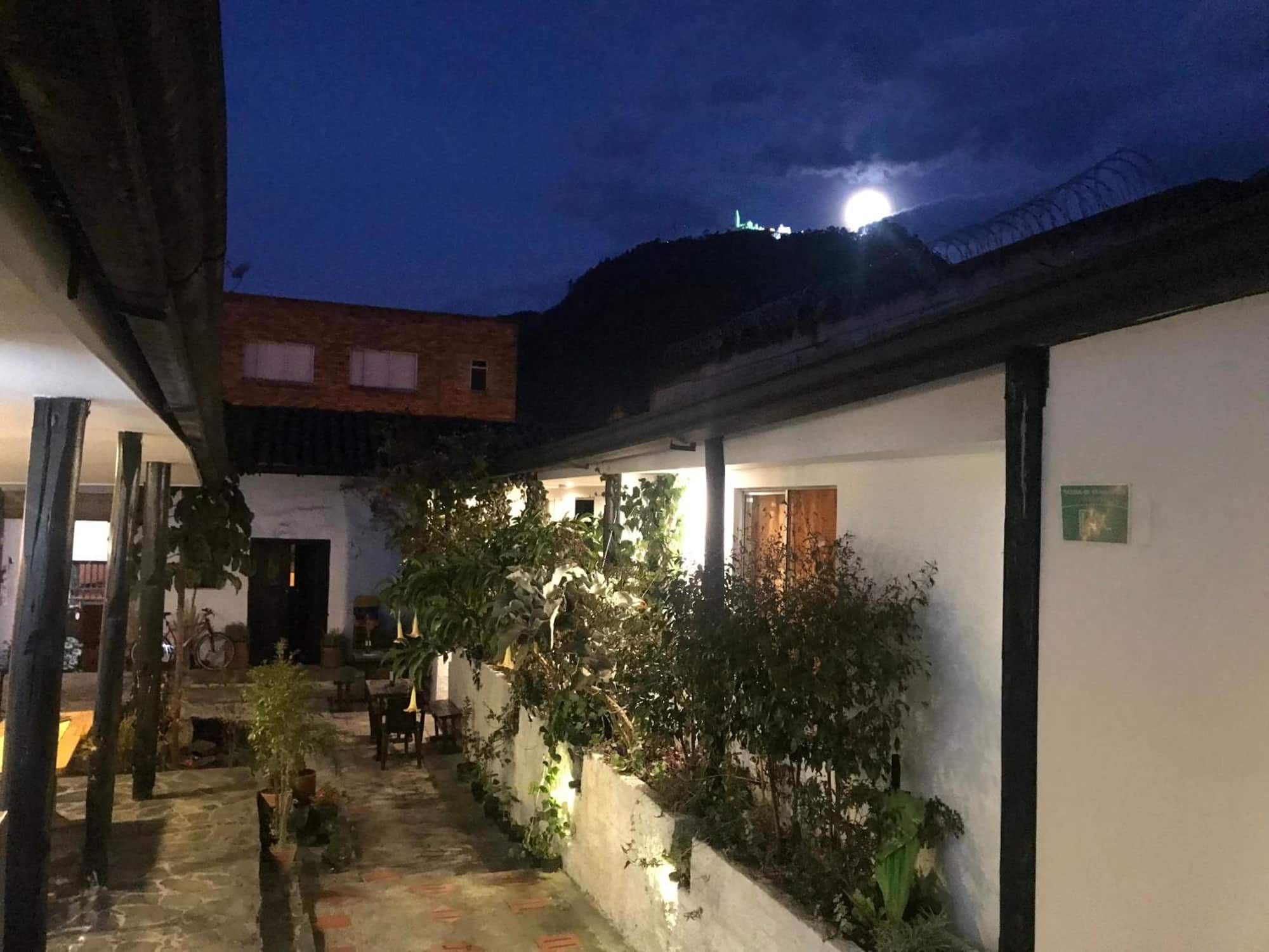 Corredor del patio de noche con la luna sobre los cerros