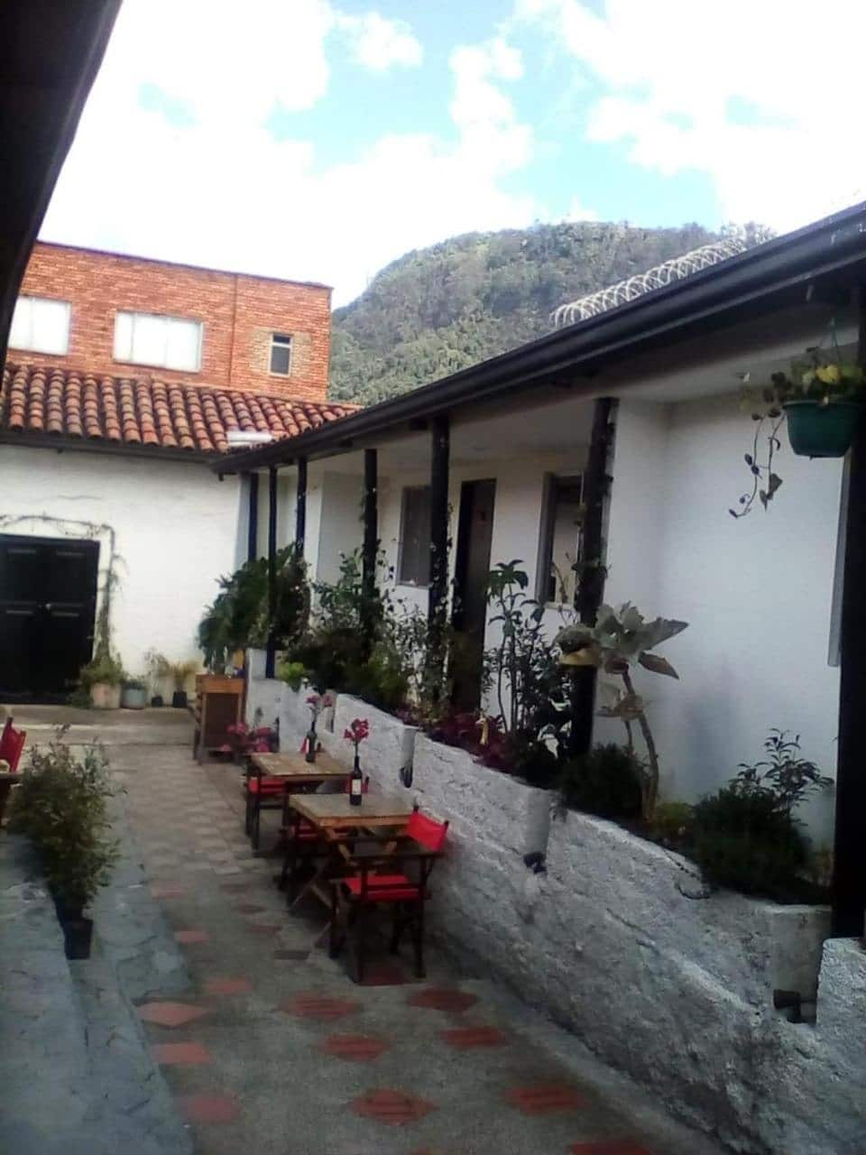 Corredor de habitaciones con matas y el cerro al fondo