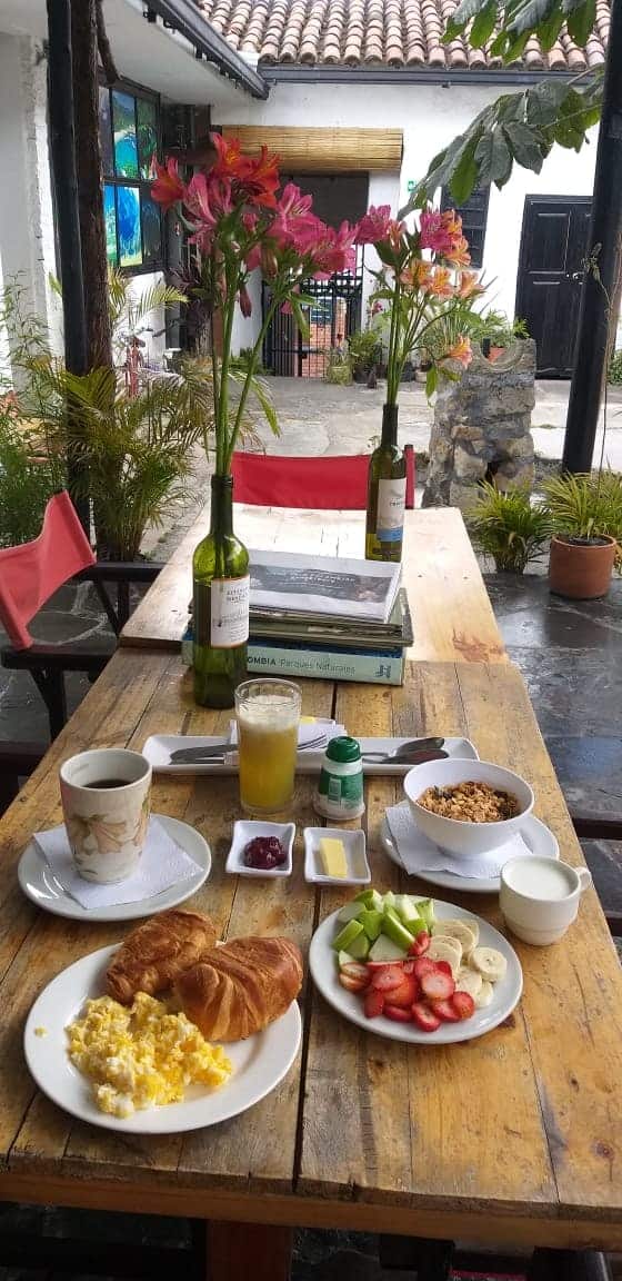 Desayuno con croissant, huevos, fruta, jugo y café en el patio