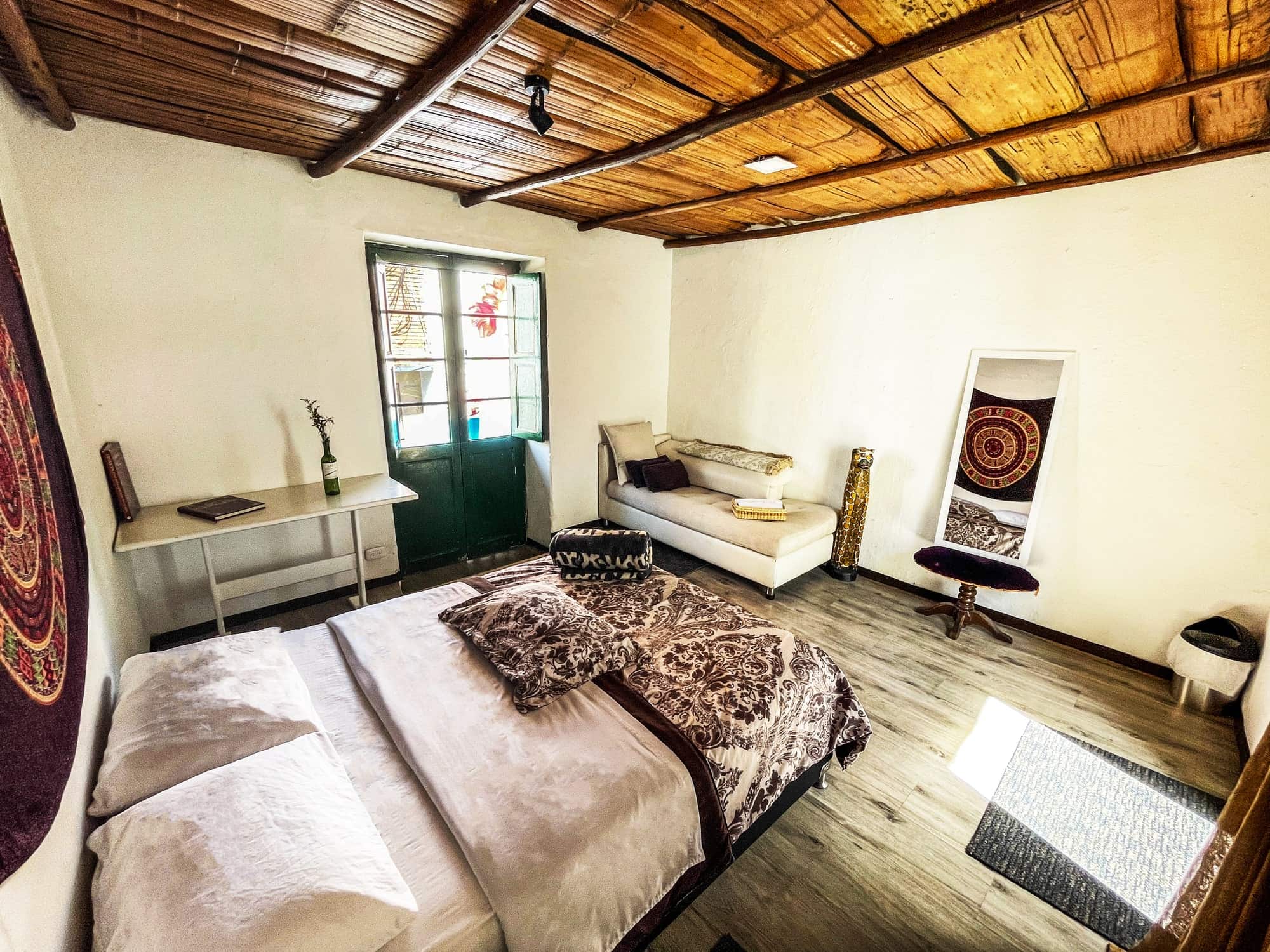 Habitación doble con cama doble, sofá, escritorio y techo de guadua
