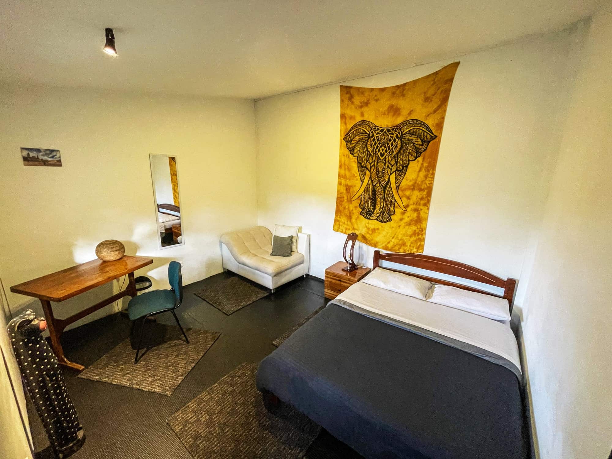 Habitación doble con cama queen, tapiz de elefante y escritorio