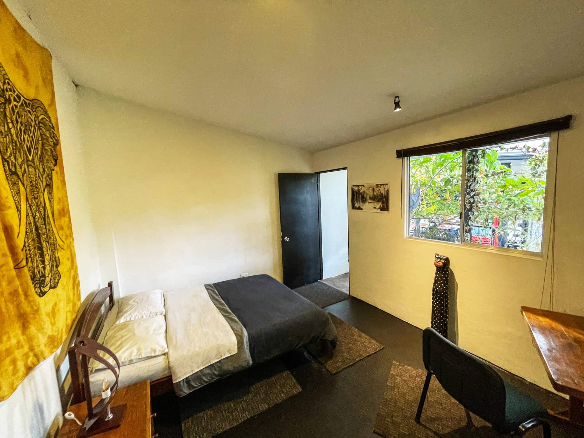 Habitación doble con cama queen y ventana hacia las plantas