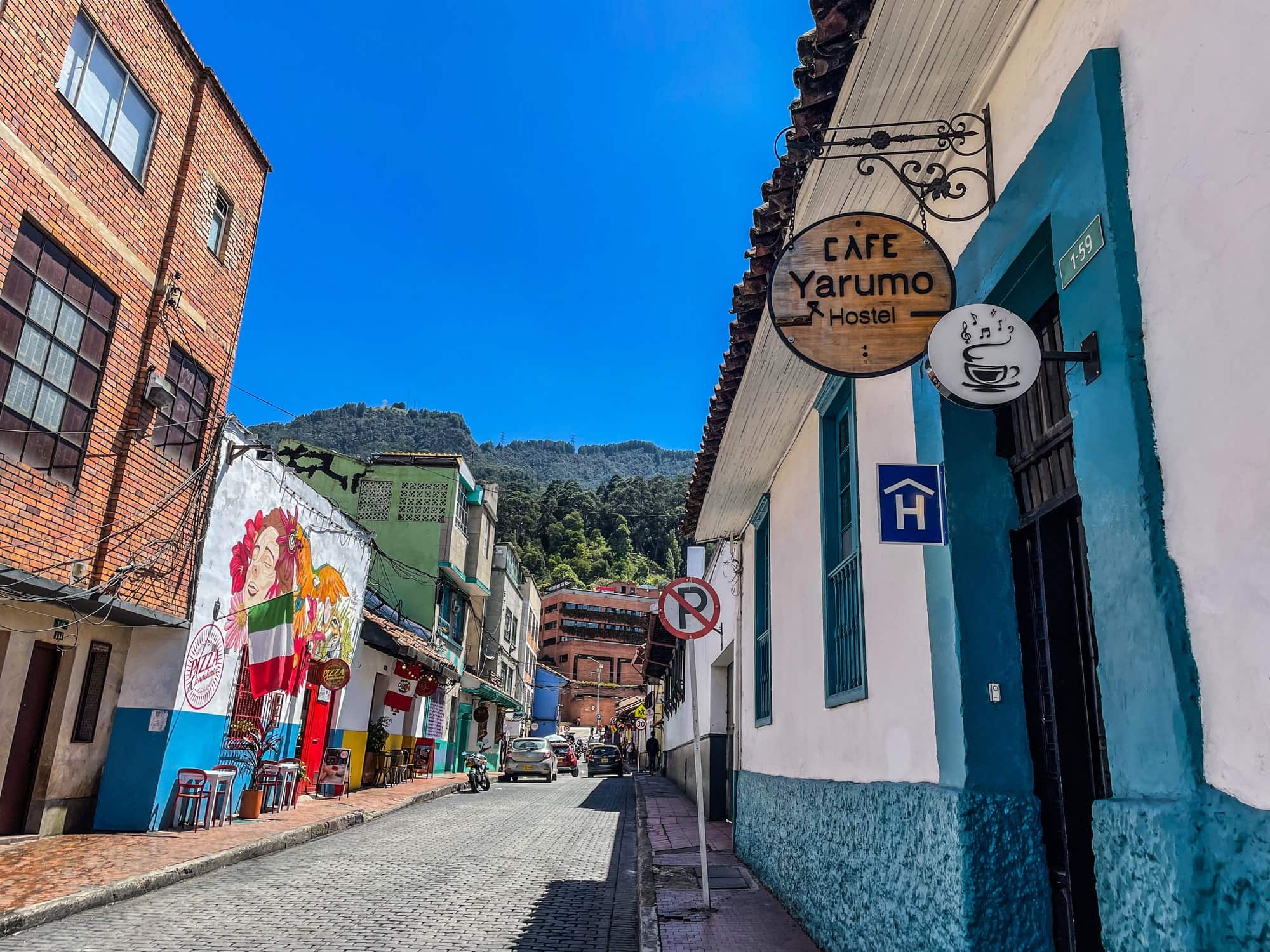Calle 12 con el aviso colgante "Café Yarumo Hostel" y los cerros