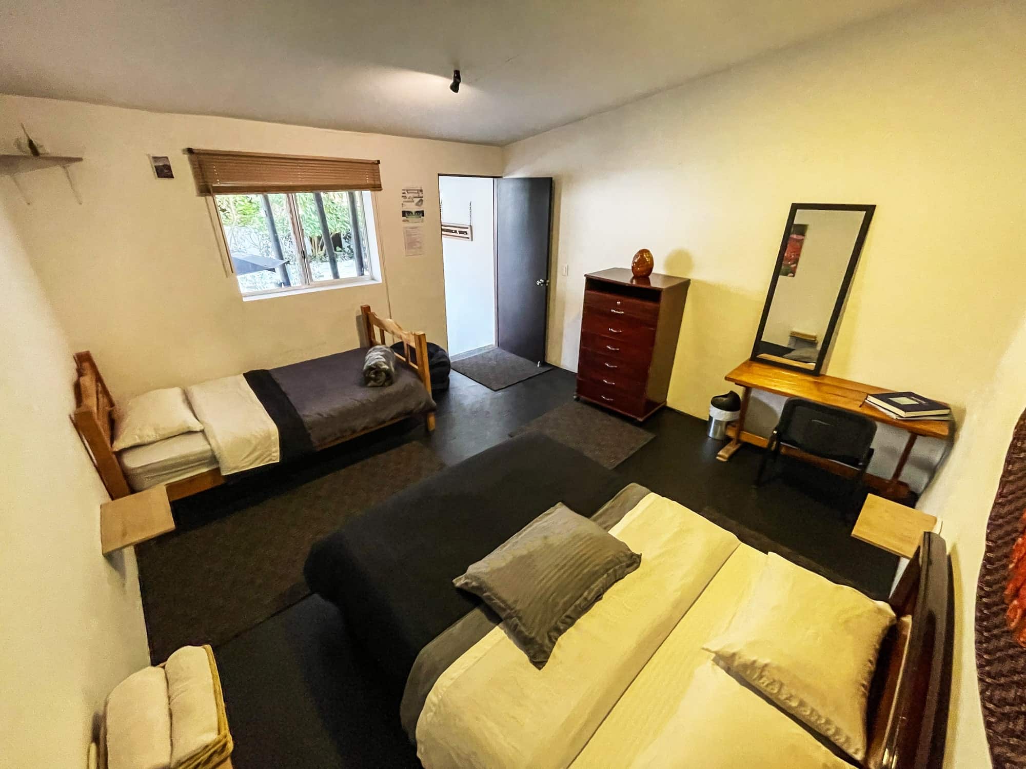 Habitación con cama doble y cama sencilla, cómoda y escritorio