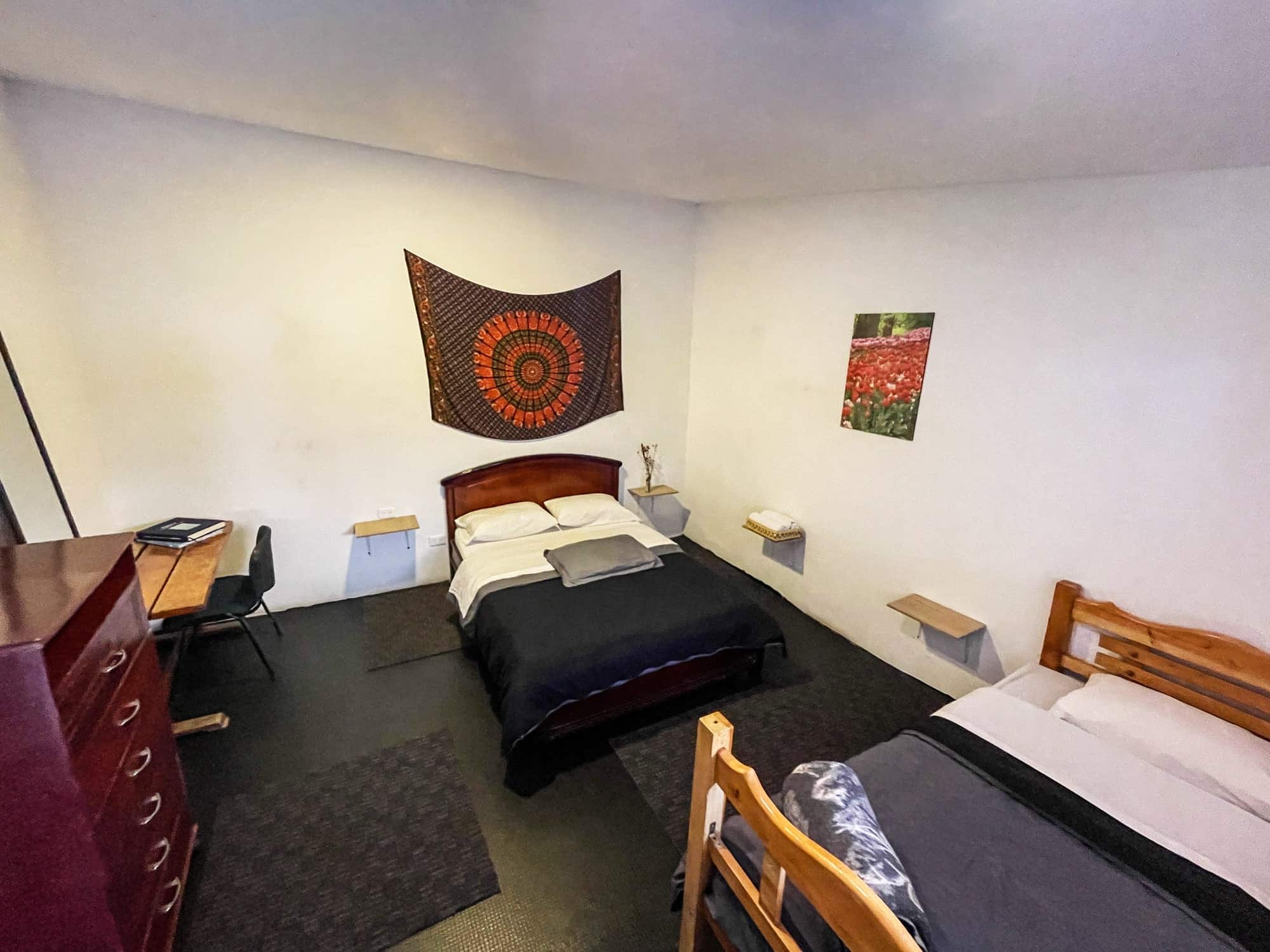 Habitación con cama doble y cama sencilla, tapiz de mandala