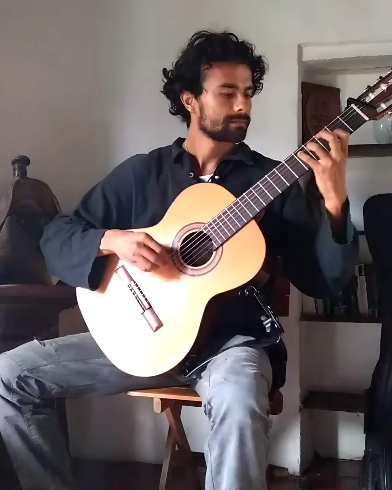 Guitarrista toca una guitarra clásica sentado en una sala de paredes blancas (archivo 2018)