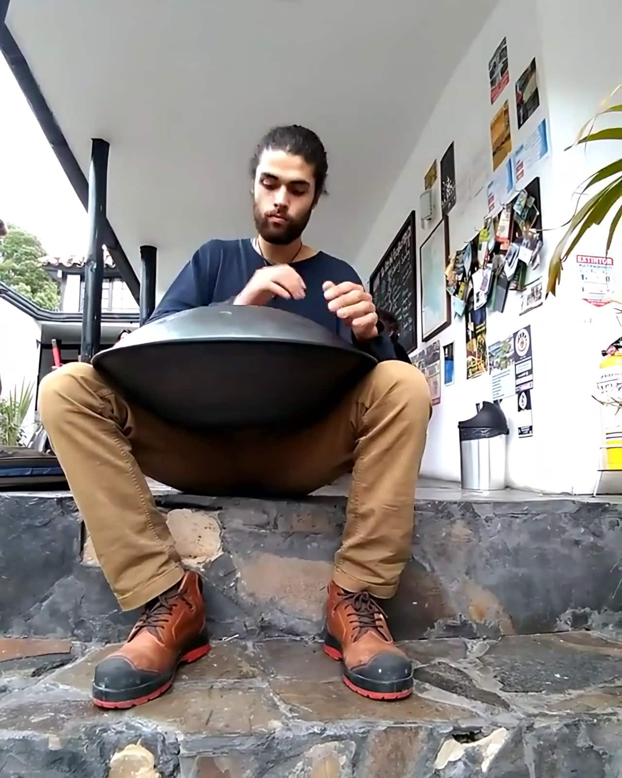 Músico toca un handpan sentado en los escalones de piedra junto al corredor (archivo 2018)